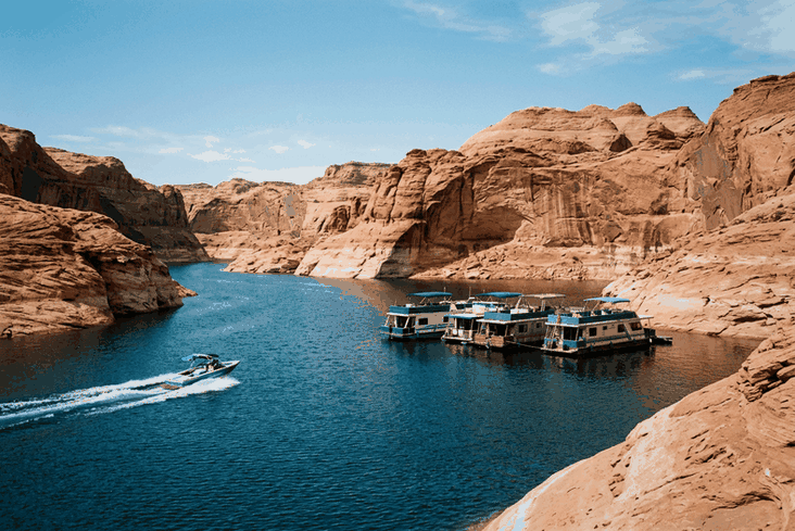 Houseboats and a ski boat on a desert canyon lake between red sandstone cliffs, as kept by many Nevada boat owners