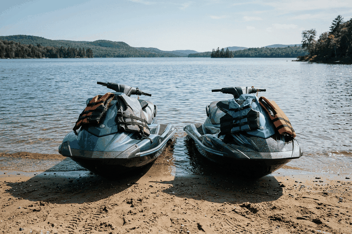 Two jet skis pulled up on a sandy lake beach