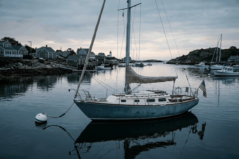 Sailboat with furled sails on a mooring in a calm harbor