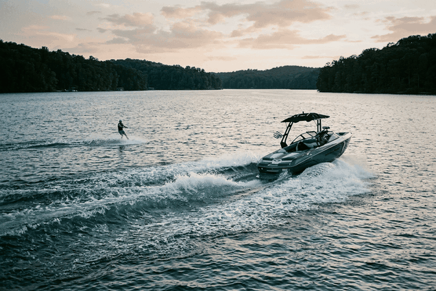 Wake boat pulling a wakeboarder across a lake